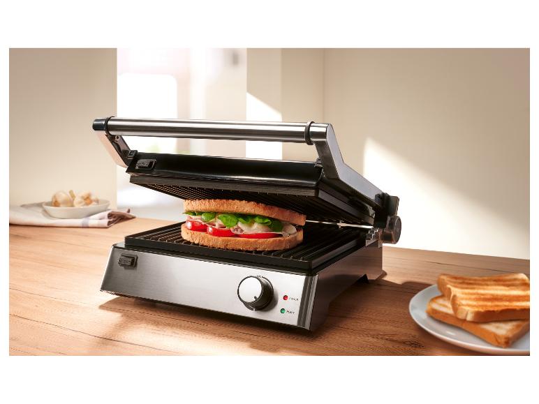 Grill z kanapką w środku i tostami na talerzu obok.
