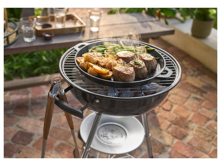 Grill z patelnią grillowanego mięsa, ziemniaków i fasolki szparagowej, z szczypcami obok.