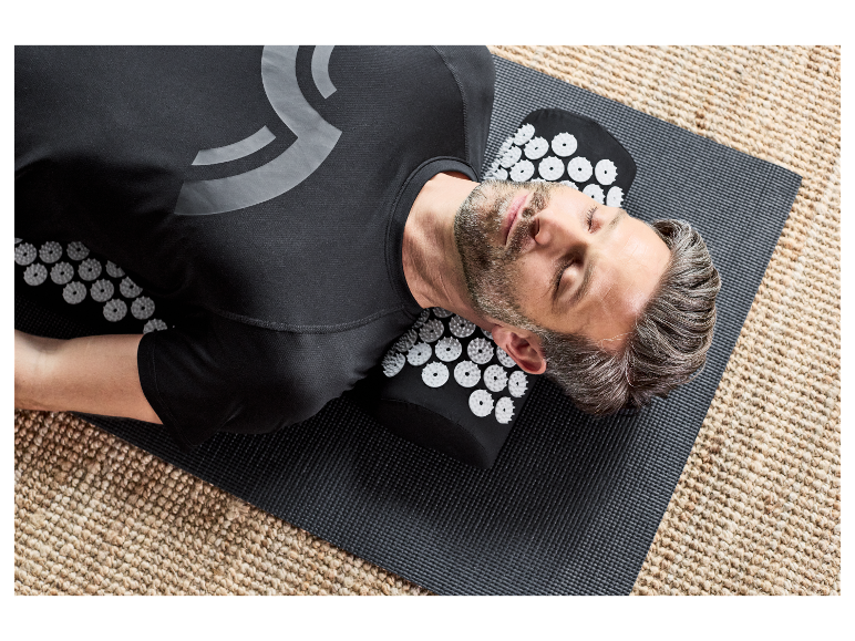 Mężczyzna relaksuje się na macie do akupresury.