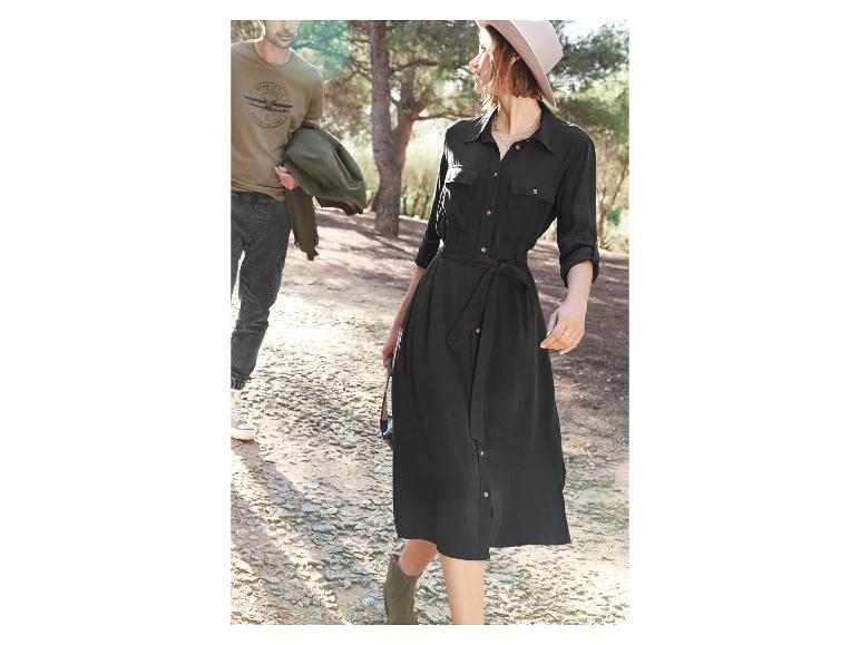 Kobieta w czarnej sukience z paskiem i kapeluszem, a mężczyzna w T-shircie z nadrukiem samolotu.