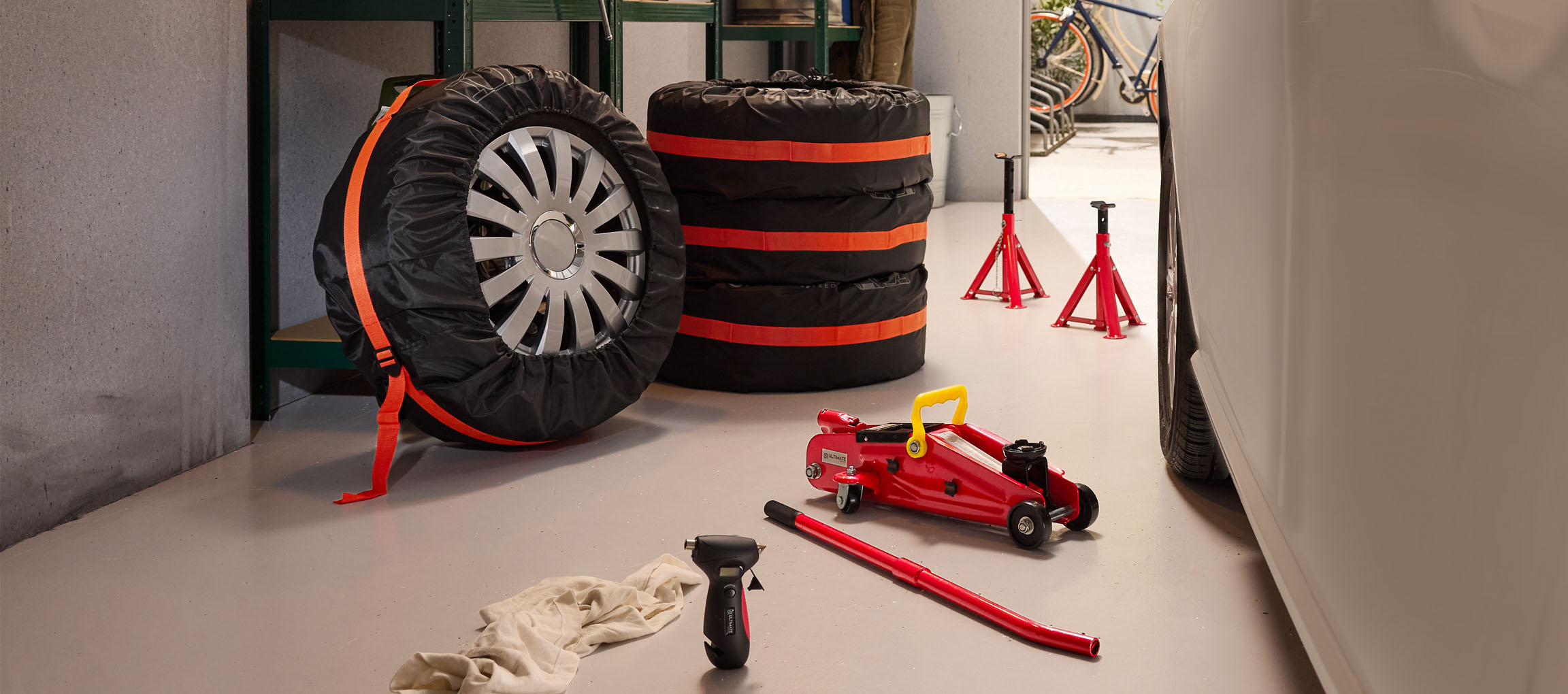 Opony samochodowe w pokrowcach, podnośnik i stojaki w garażu.