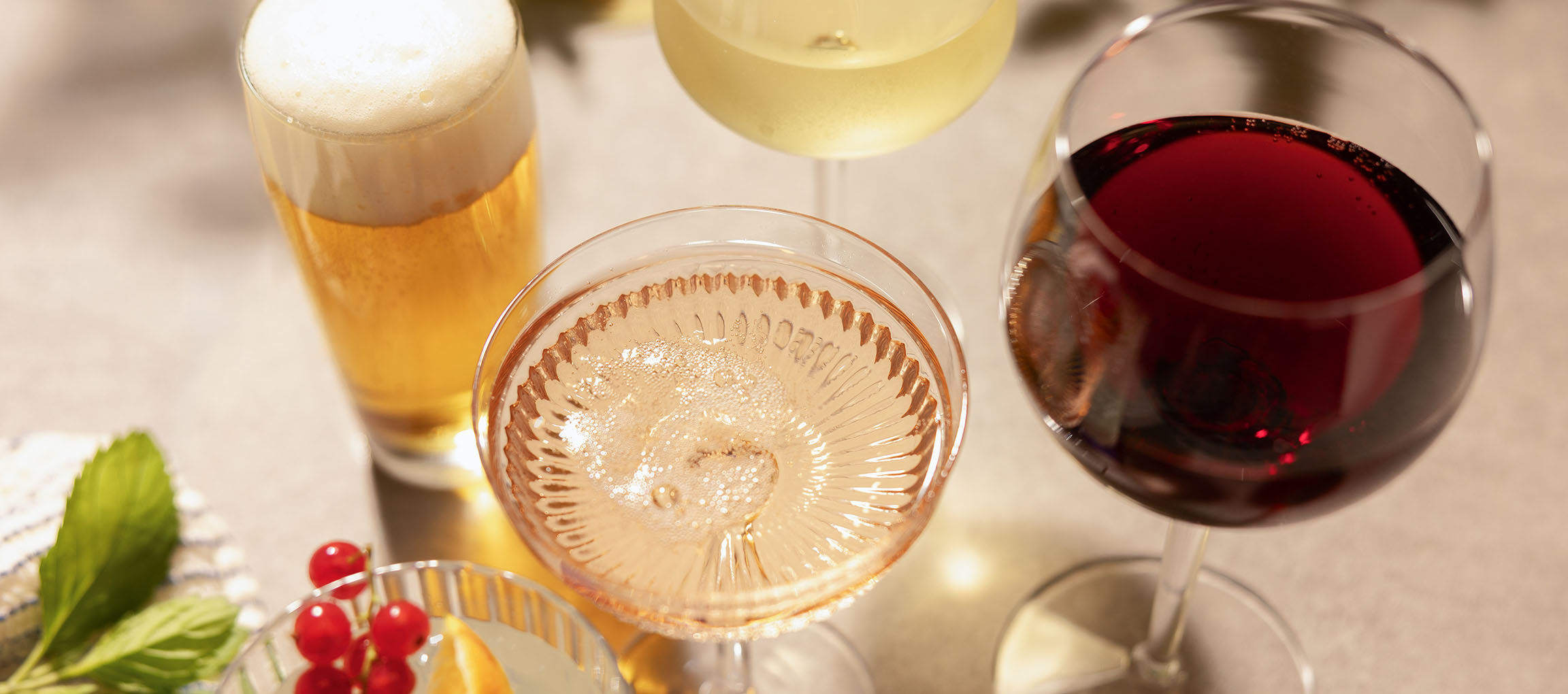Piwo, wino różowe i czerwone w kieliszkach, z jagodami i miętą.