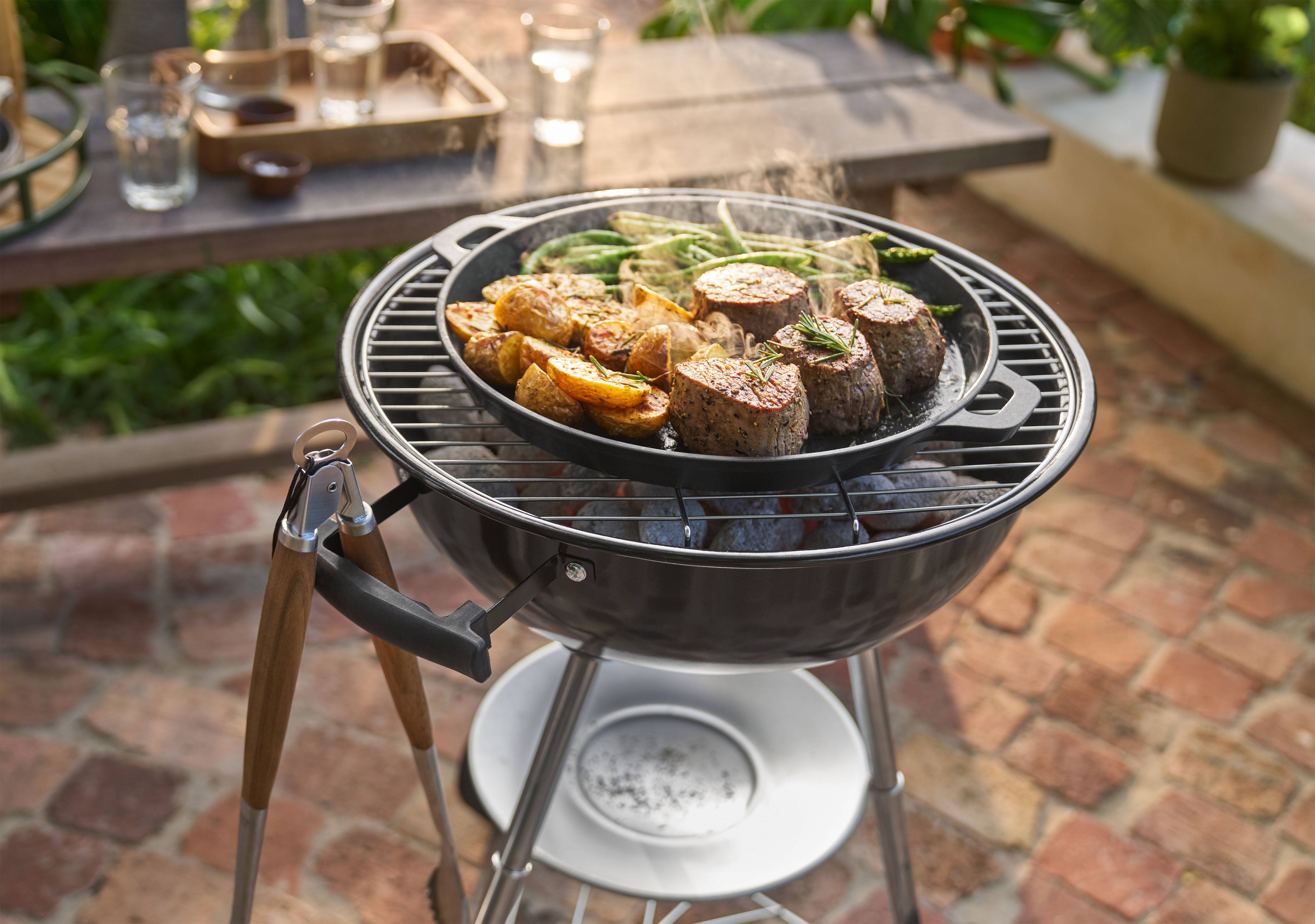 Grill z mięsem, ziemniakami i fasolką szparagową gotującymi się na patelni na zewnątrz.