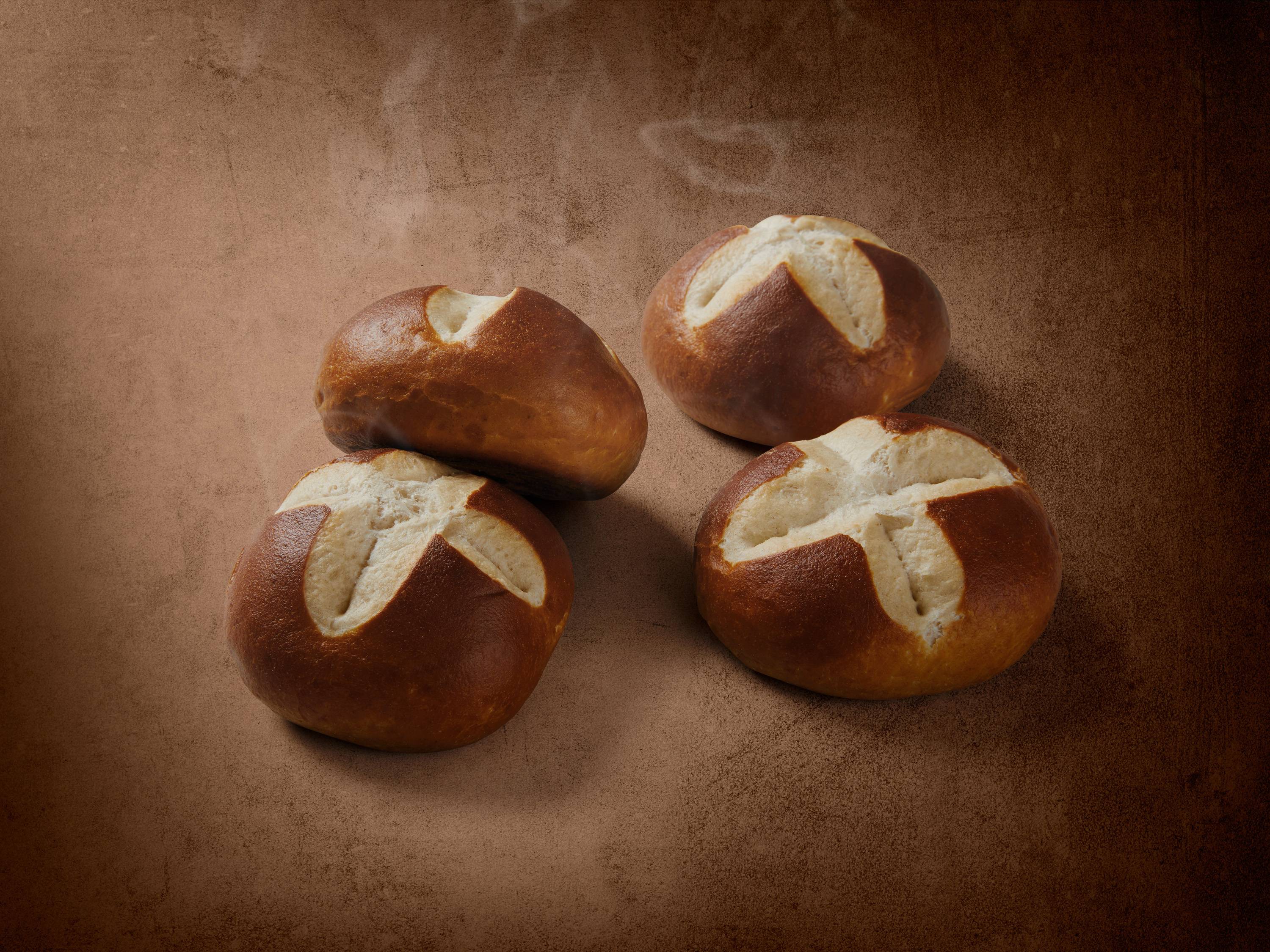 Cztery okrągłe bułki bawarskie na brązowym tle.