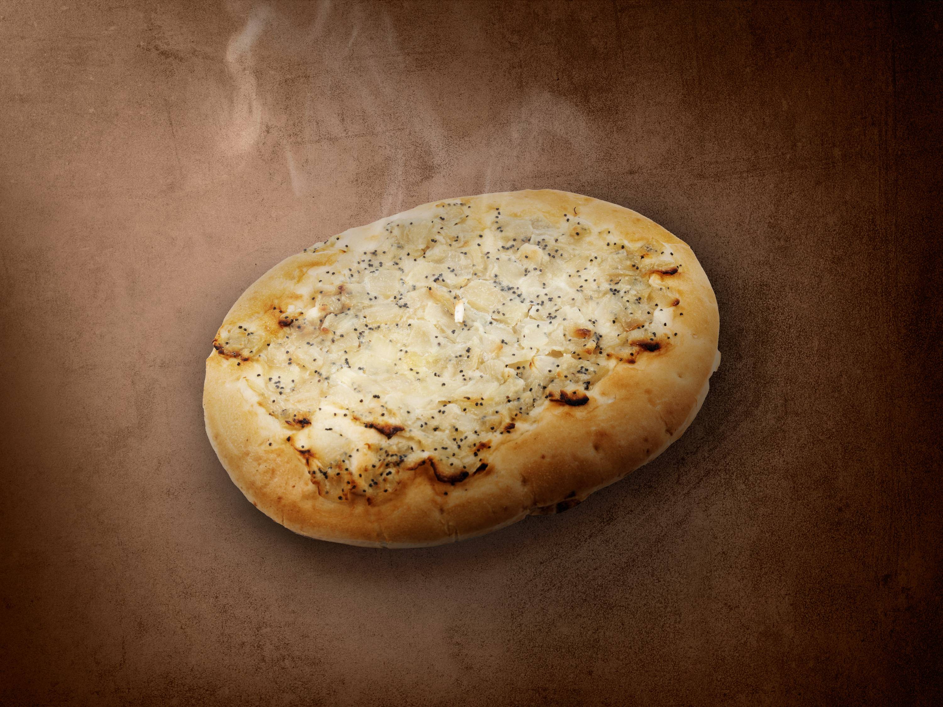 Płaski chleb z cebulą i makiem na brązowym tle z parą.