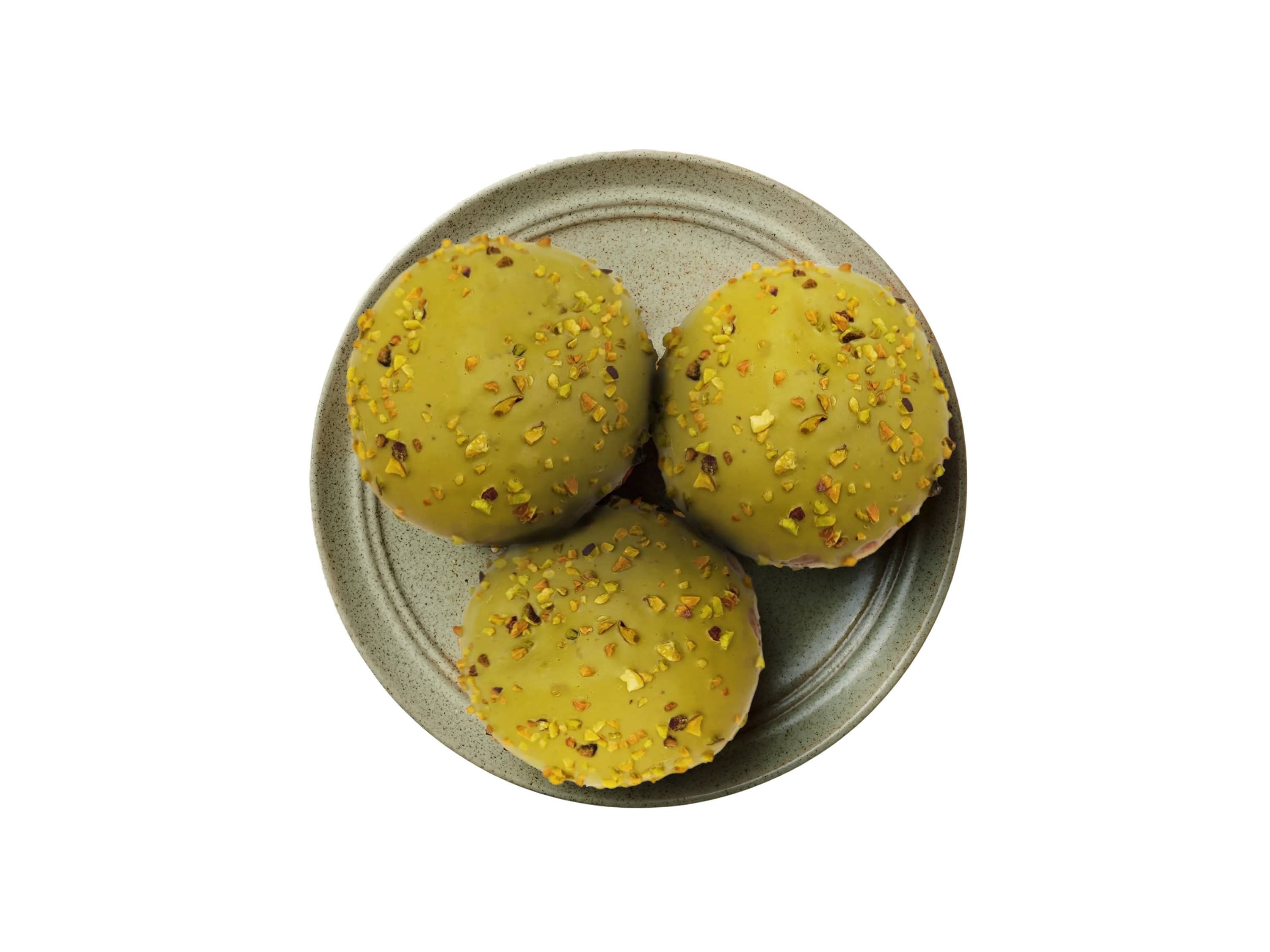 Trzy pączki pistacjowe z posypką na talerzu.