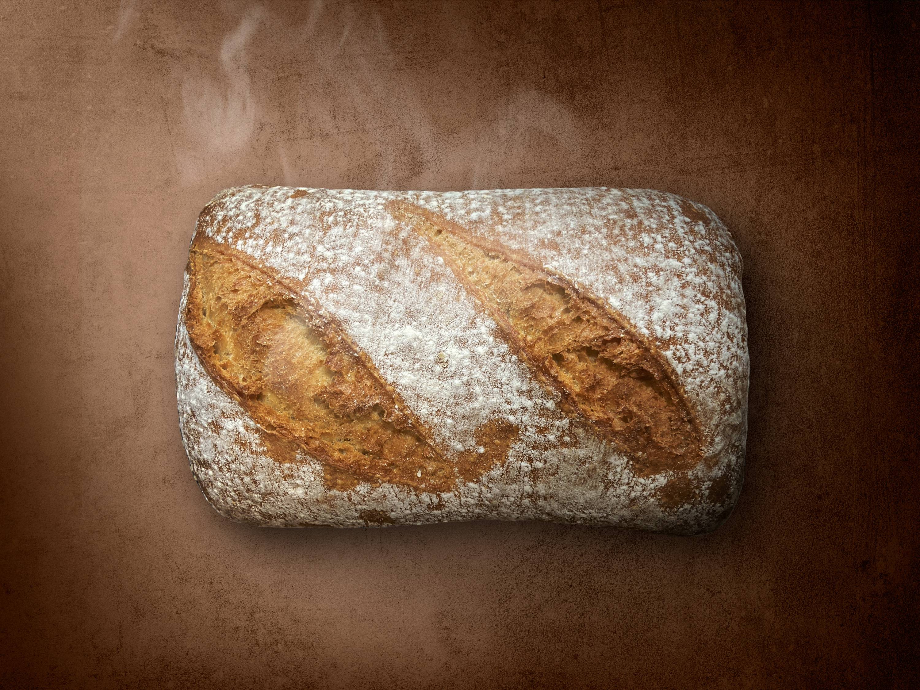 Chleb ze skyrem na kamieniu na brązowym tle z parą