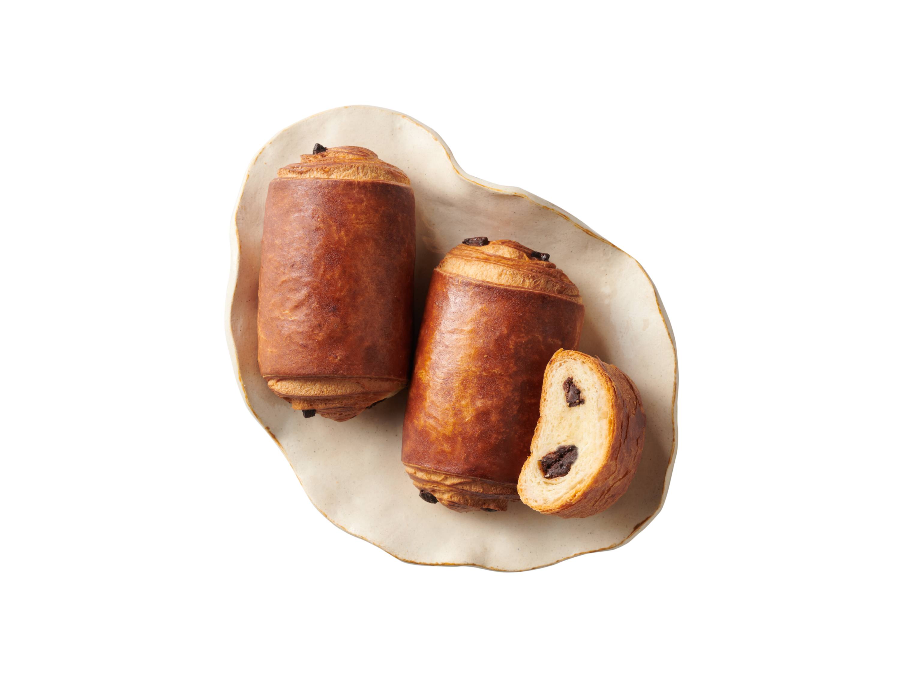 Dwa pain au chocolat i jeden przekrojony na beżowym talerzu.