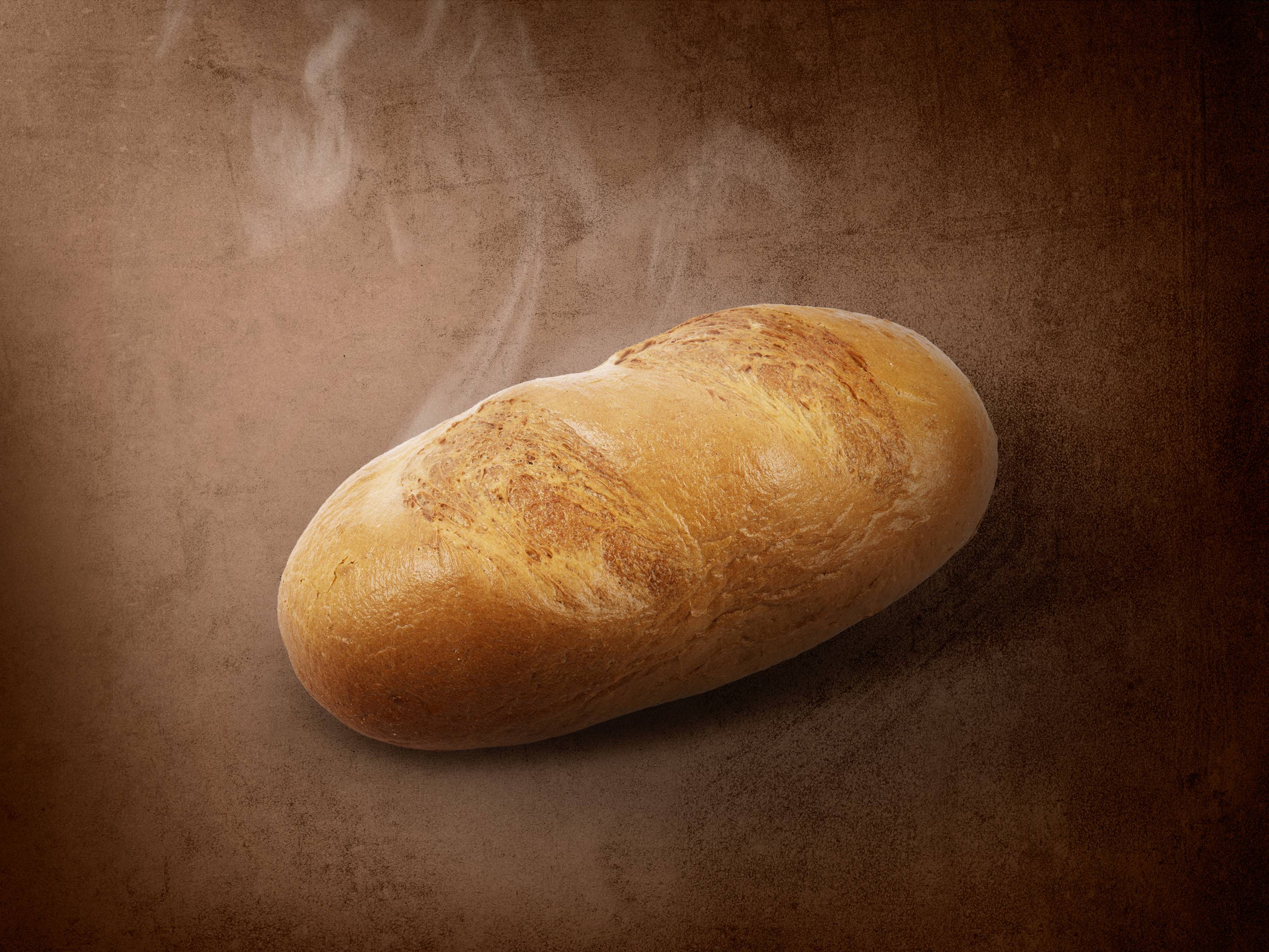 Gorący bochenek chleba na brązowym tle z unoszącą się parą.