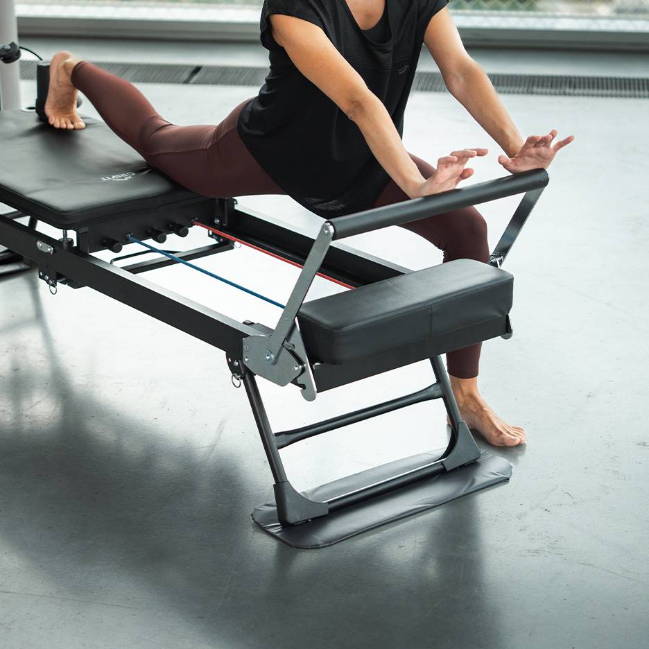 Kobieta ćwicząca na maszynie do Pilatesu w odzieży sportowej
