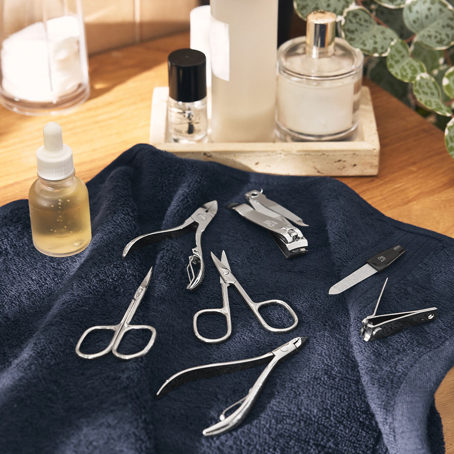 Zestaw do manicure z cążkami, nożyczkami i pilnikami na granatowym ręczniku.