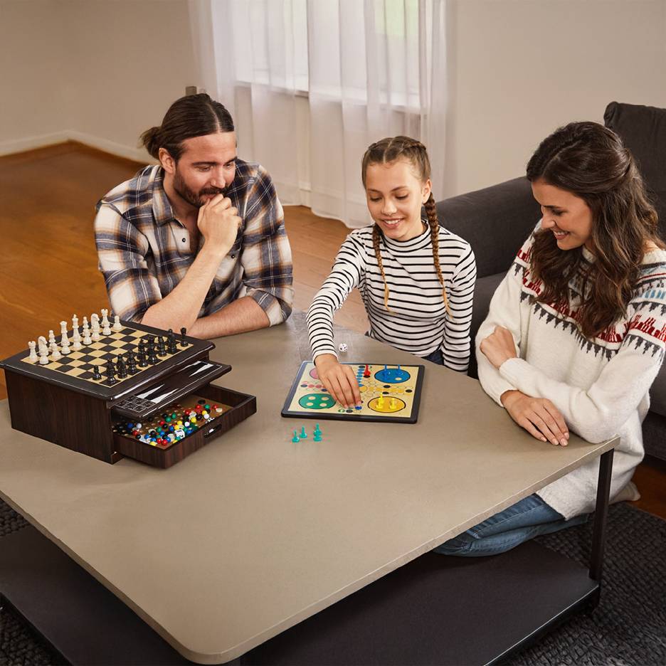 Rodzina gra w gry planszowe, w tym szachy i Ludo, na stoliku kawowym.