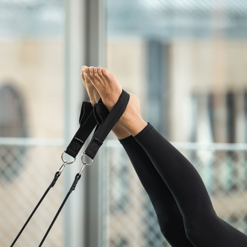 Osoba ćwicząca Pilates ze stopami w paskach.