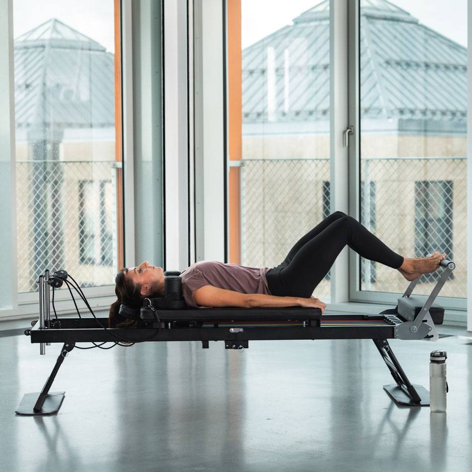 Kobieta ćwiczy Pilates na maszynie reformer.
