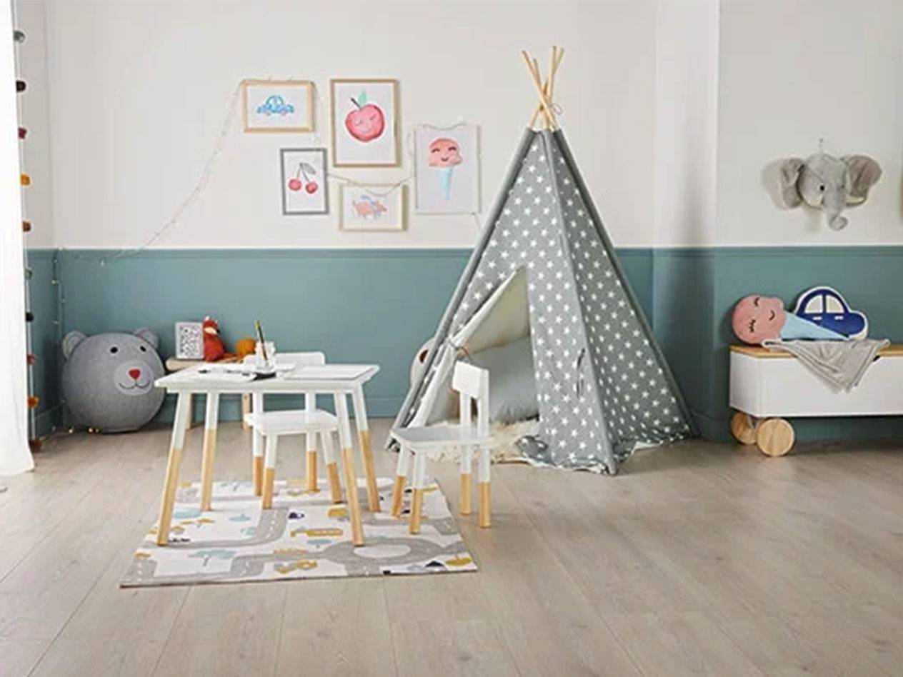 Pokój dziecięcy z namiotem tipi, stołem i krzesłami, skrzynią na zabawki i obrazkami na ścianie.