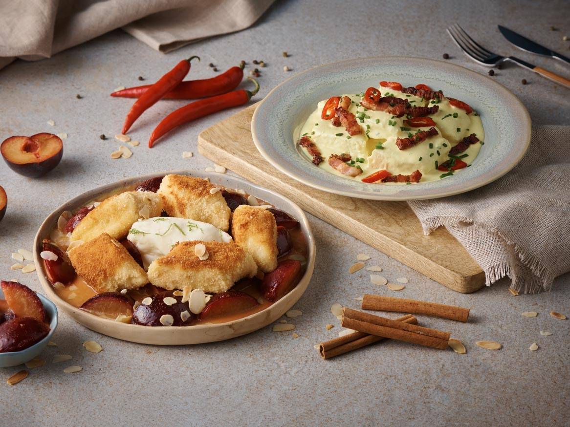 Słodkie knedle ze śliwkami i pikantne puree ziemniaczane z boczkiem na stole.