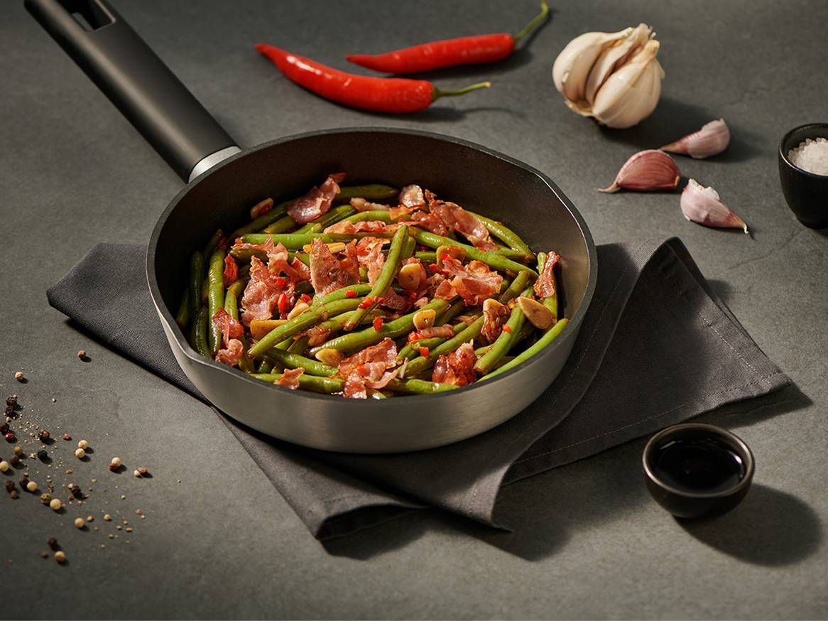 Zielona fasolka z boczkiem i czosnkiem na patelni, z papryczkami chili i przyprawami.