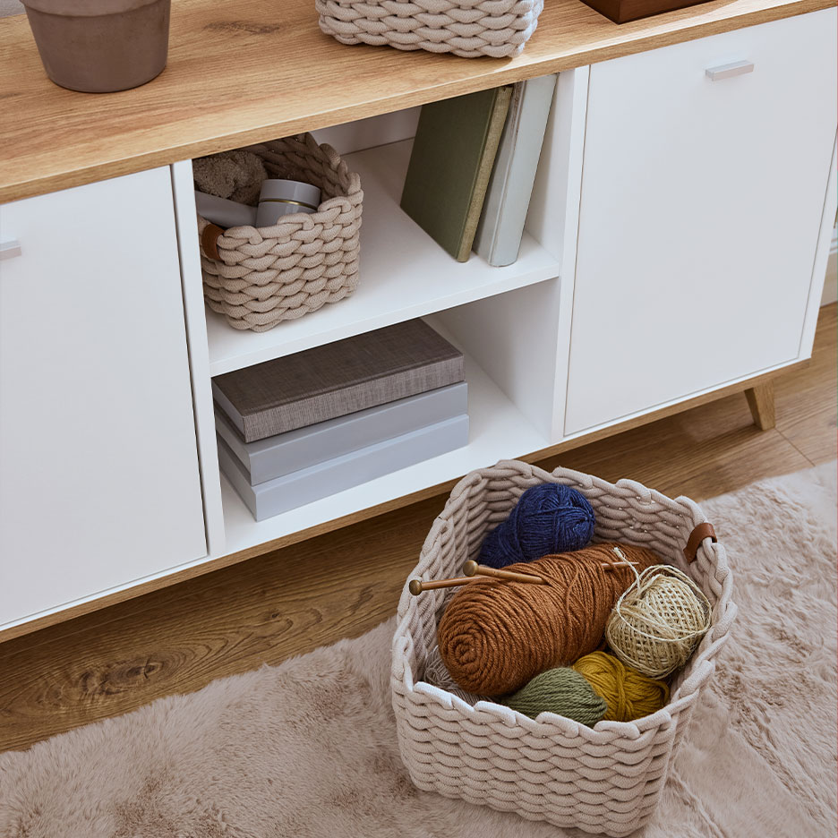 Drewniana szafka do przechowywania z plecionymi koszami i włóczką.