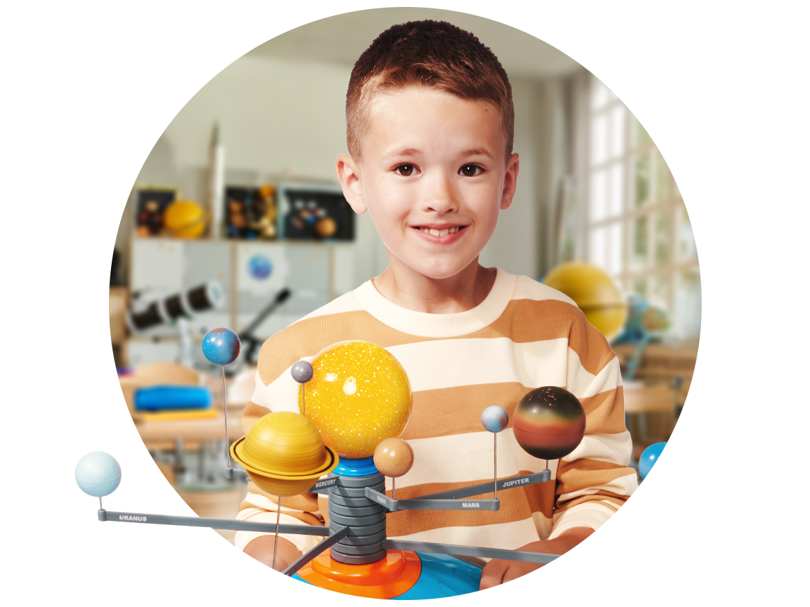 Uśmiechnięty chłopiec trzyma model Układu Słonecznego w klasie.