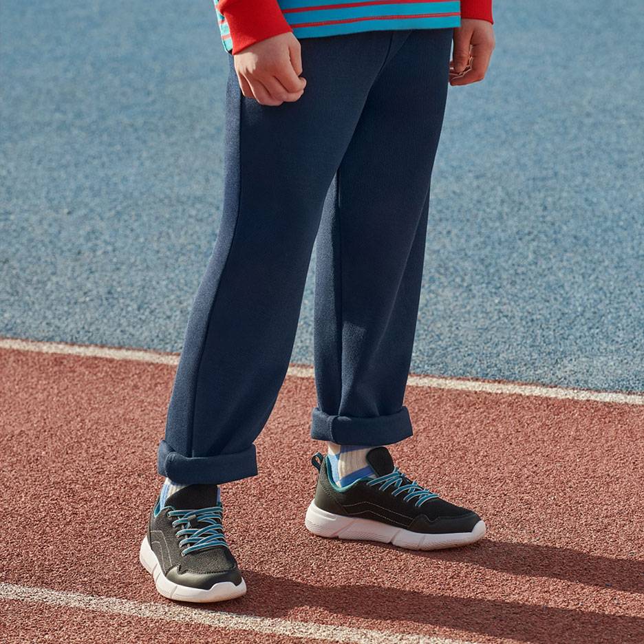 Granatowe spodnie dresowe i czarne sneakersy z niebieskimi sznurówkami na bieżni.