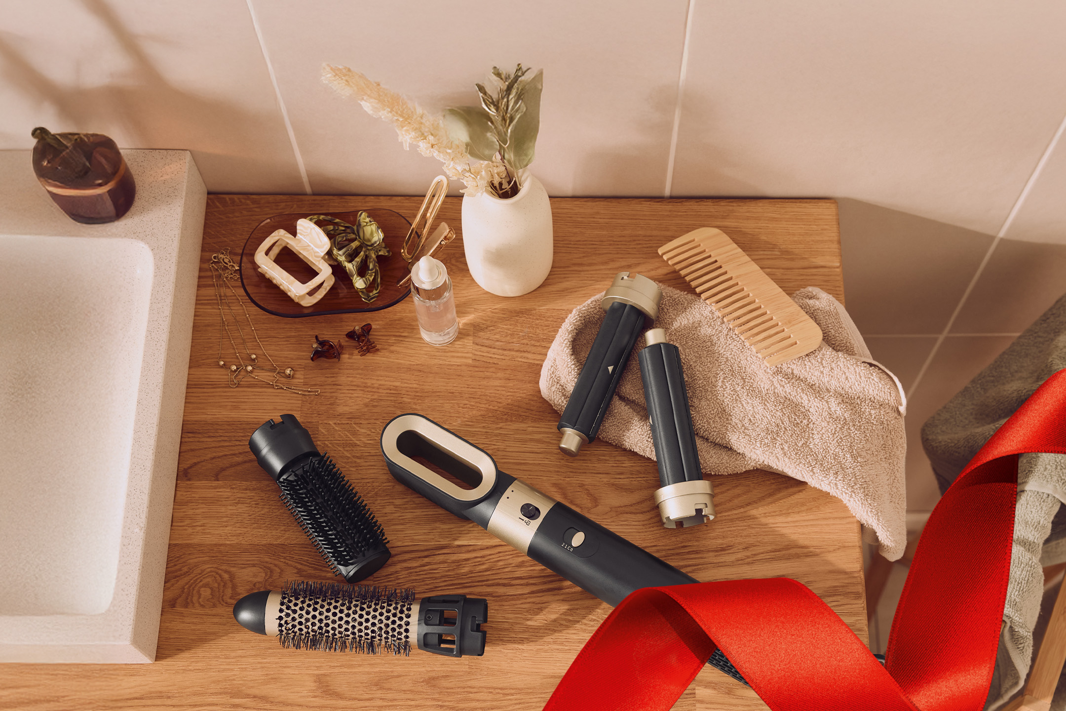 Zestaw do stylizacji włosów z suszarką, szczotkami, grzebieniem i akcesoriami na drewnianym blacie.