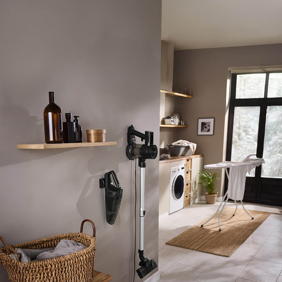 Odkurzacz pionowy i ręczny w pralni z deską do prasowania i pralką.