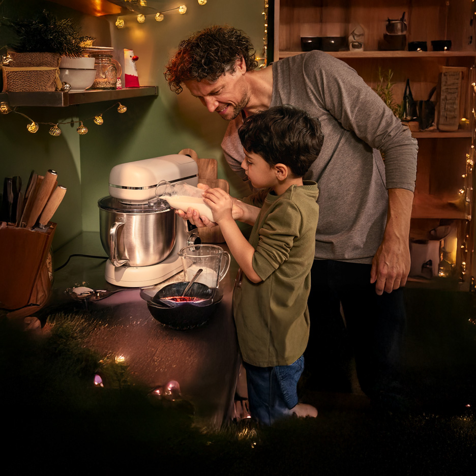 Ojciec i syn pieką, dodając mleko do miksera kuchennego Silvercrest.