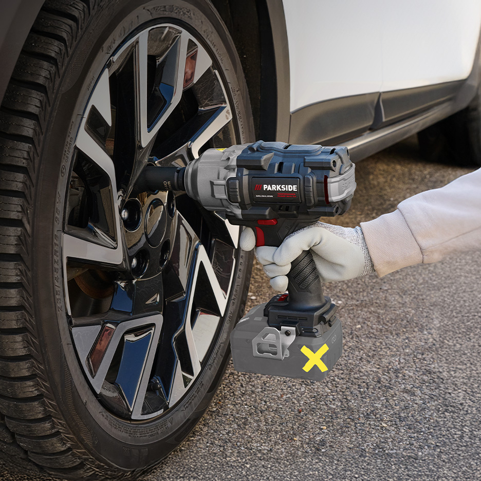Osoba używająca klucza udarowego Parkside do odkręcania koła samochodu.