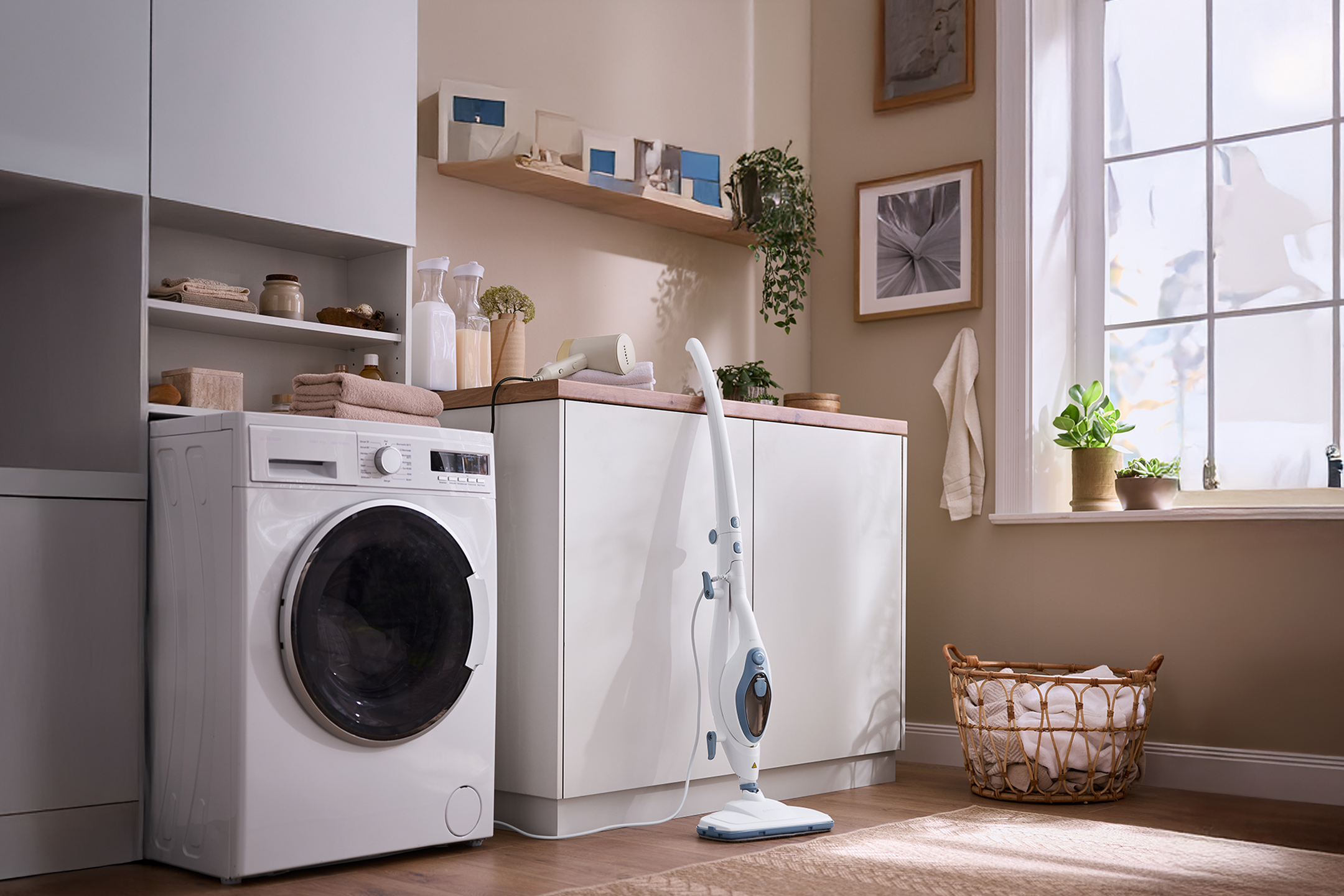 Pralka w pralni z szafkami, półkami, koszem na pranie i mopem parowym.