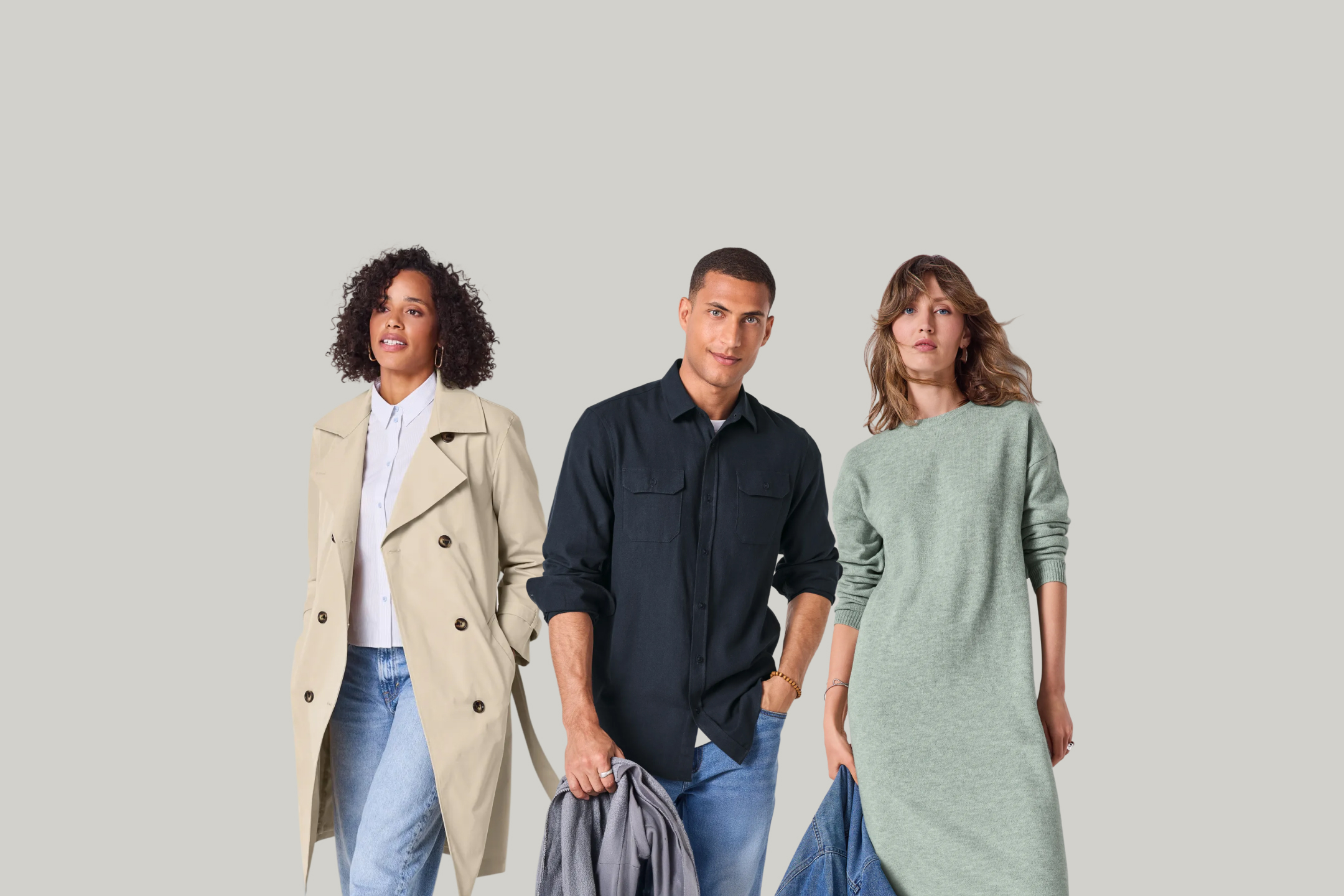 Trzy osoby w modnych ubraniach: beżowym trenczu, granatowej koszuli i zielonej sukience.