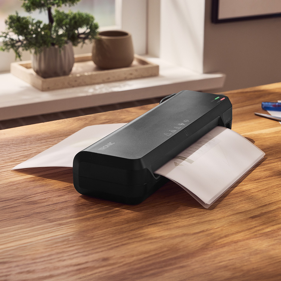 Czarna laminarka TRONIC laminująca dokumenty na drewnianym biurku.