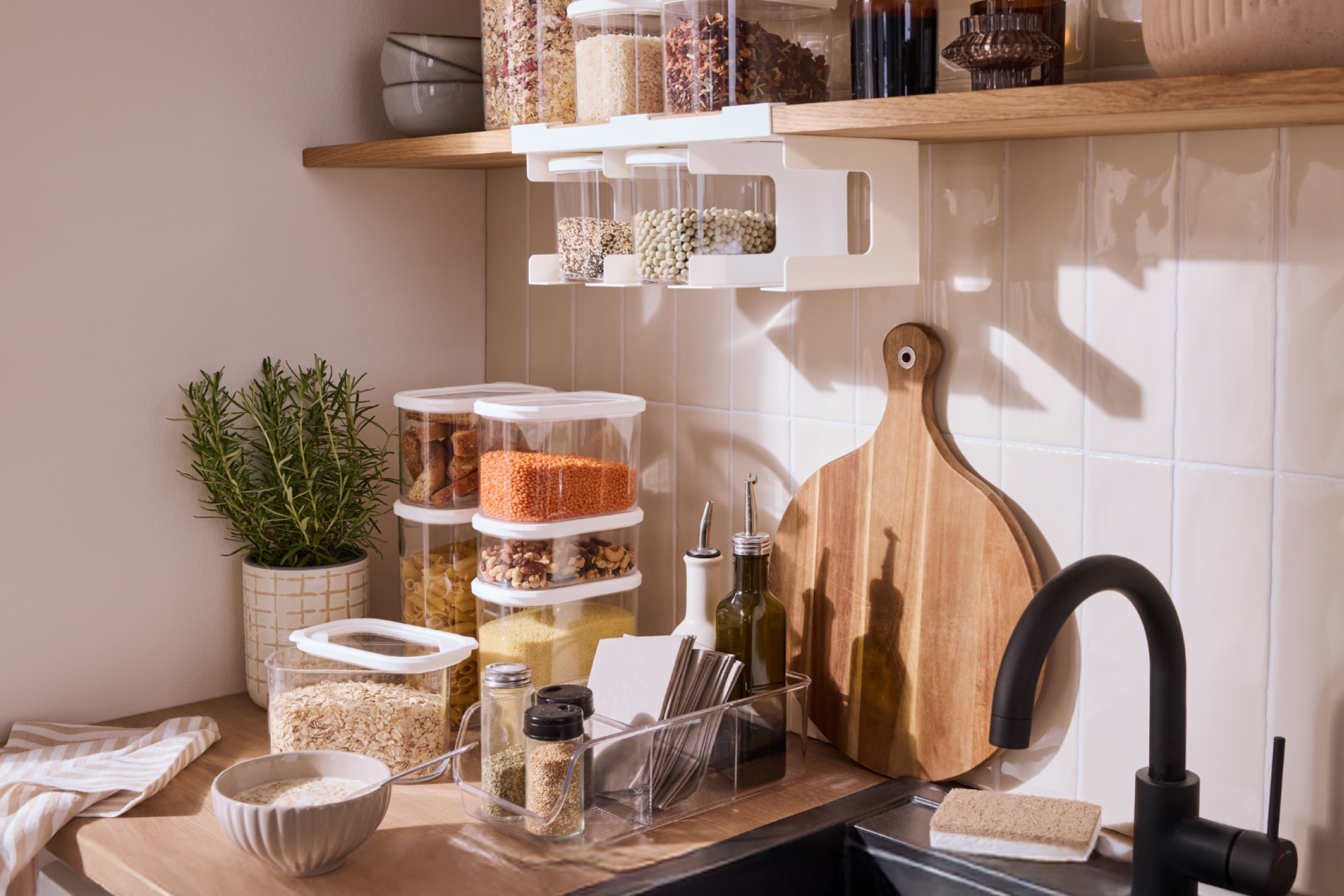 Kuchnia z pojemnikami na żywność, przyprawy, deskami do krojenia i czarnym kranem.