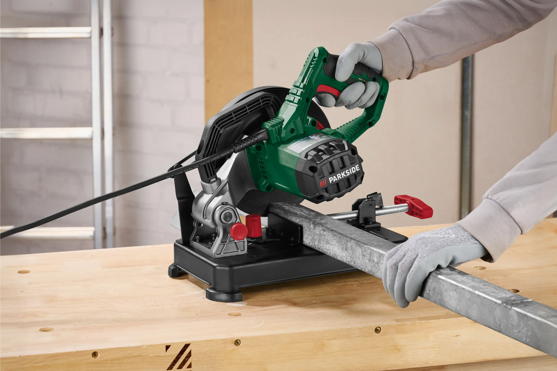 Ukośnica do metalu tnąca metalowy profil na drewnianym stole warsztatowym.