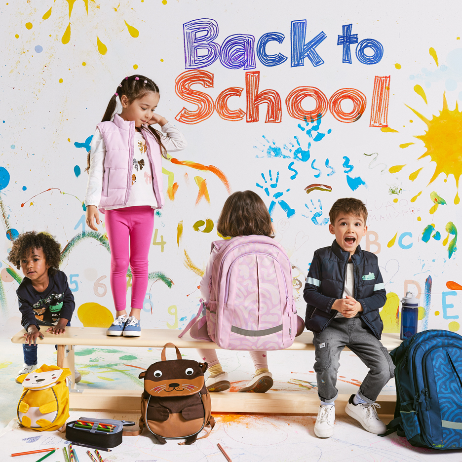 Czworo dzieci z plecakami i przyborami szkolnymi, z napisem „Back to School” na kolorowym tle.