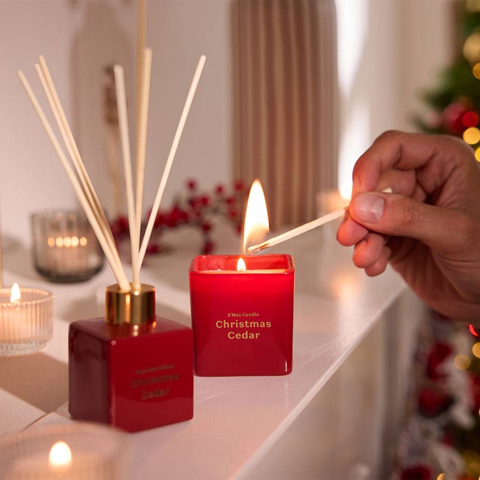 Czerwony dyfuzor i świeca 'Christmas Cedar' zapalane zapałką.