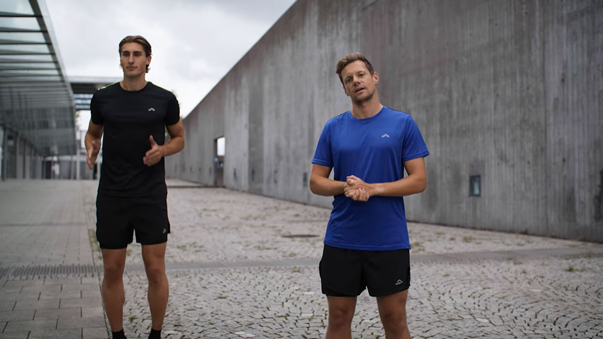 Dwóch mężczyzn w czarnych i niebieskich strojach sportowych na zewnątrz.