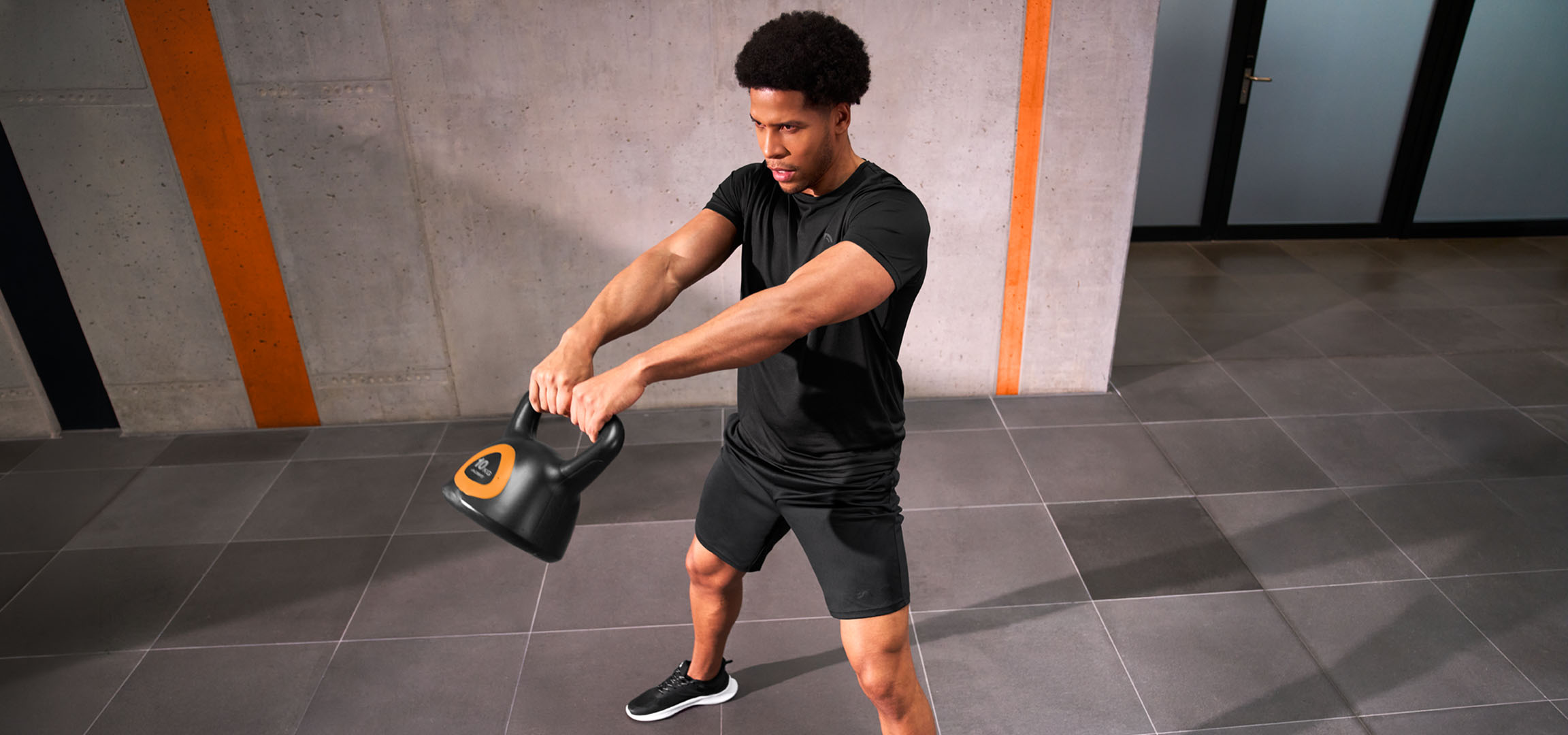 Grafika została wygenerowana przy użyciu AI: Mężczyzna trenujący z czarno-pomarańczowym odważnikiem kettlebell.