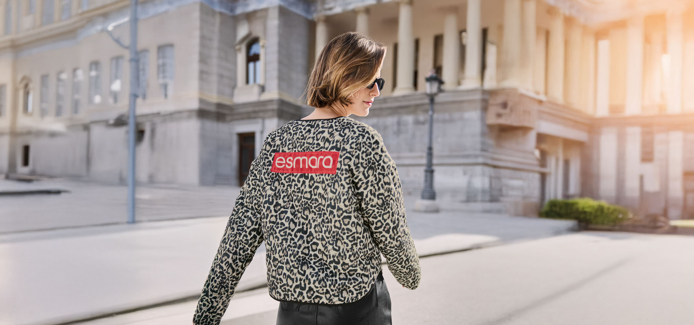 Kobieta w kurtce w panterkę Esmara, okularach przeciwsłonecznych, na ulicy.