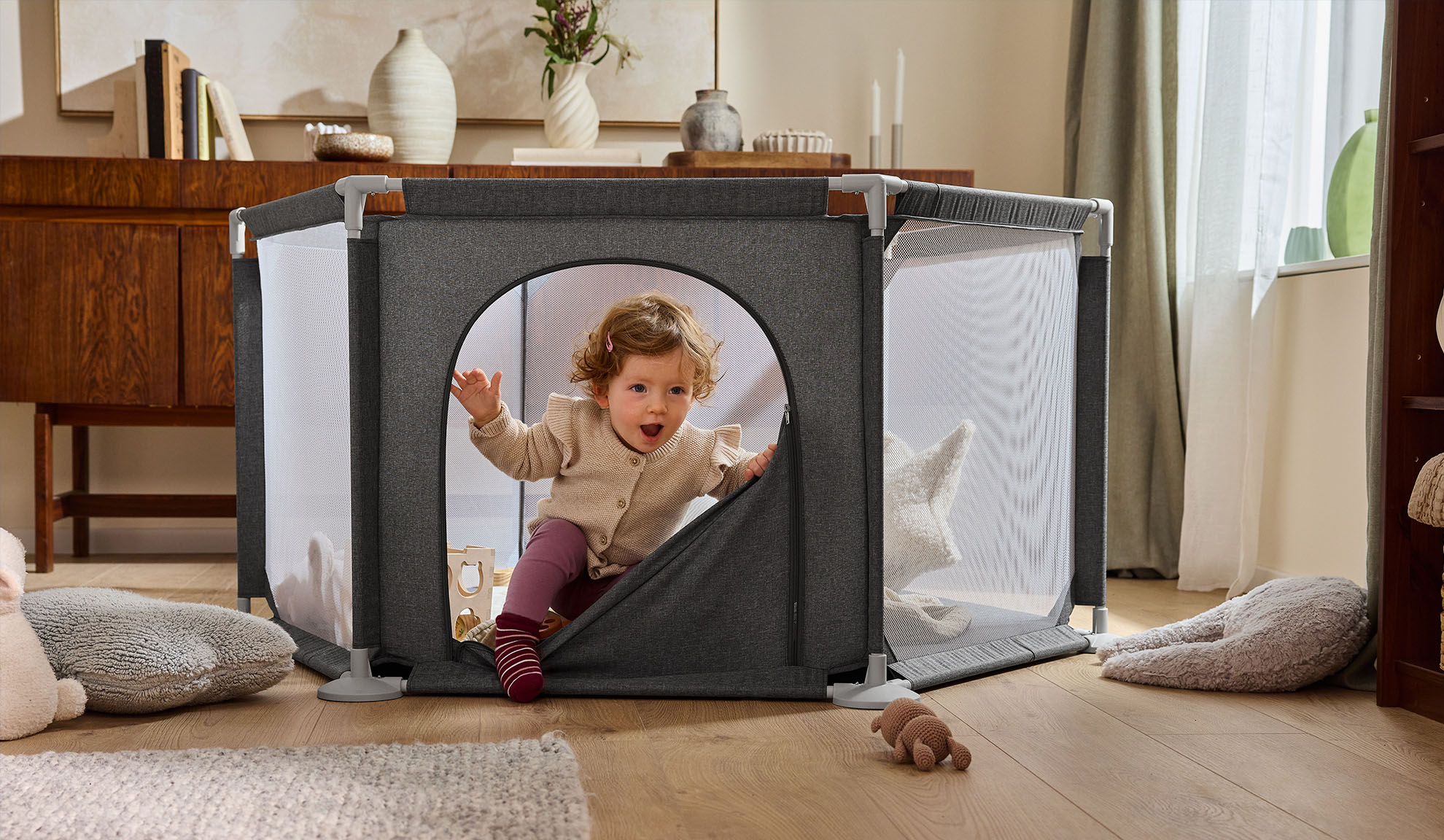 Szczęśliwe dziecko wychodzące z szarego kojca w przytulnym salonie.