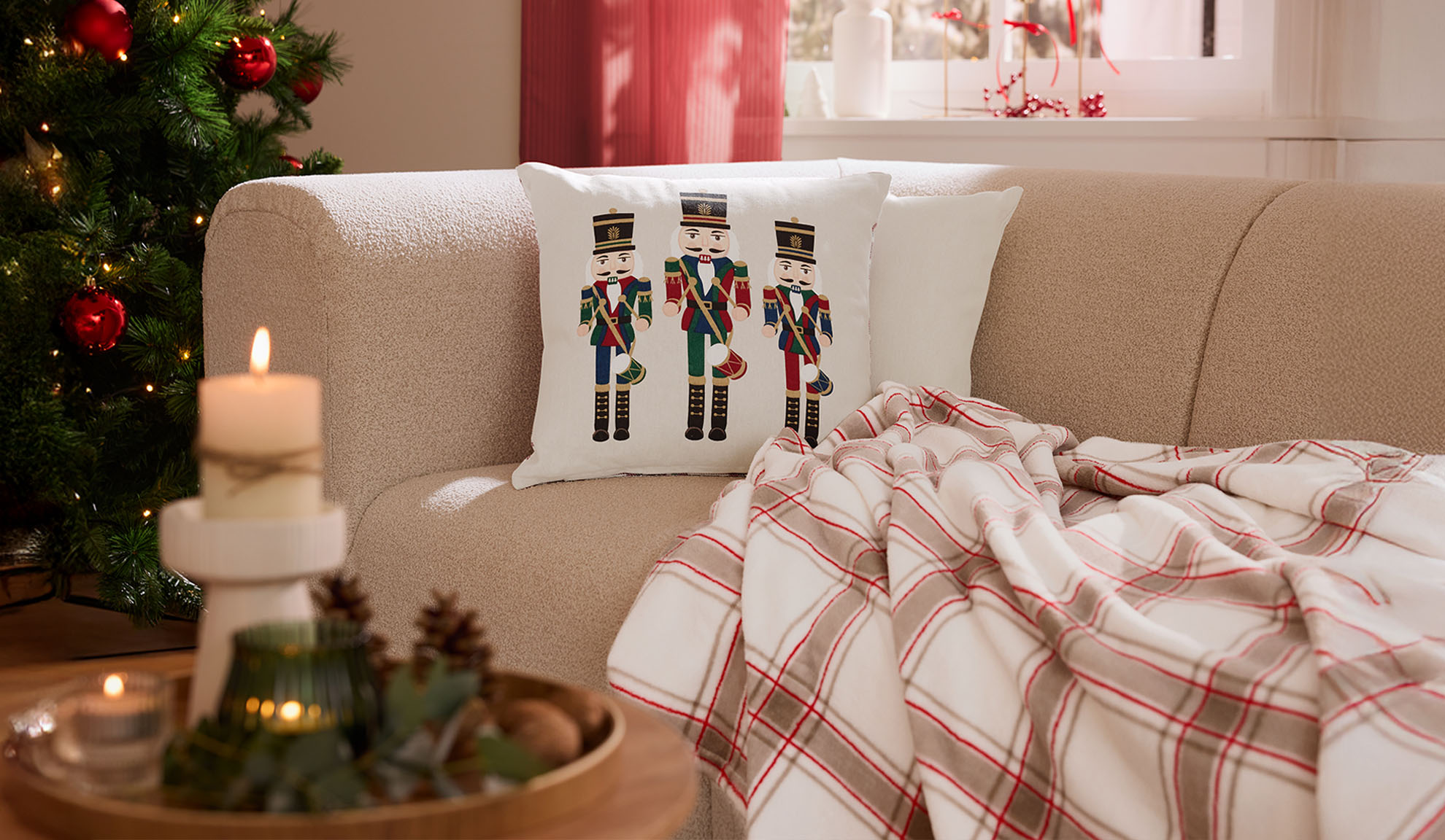 Świąteczny salon z sofą, poduszkami z dziadkami do orzechów, pledem w kratę i świecami.