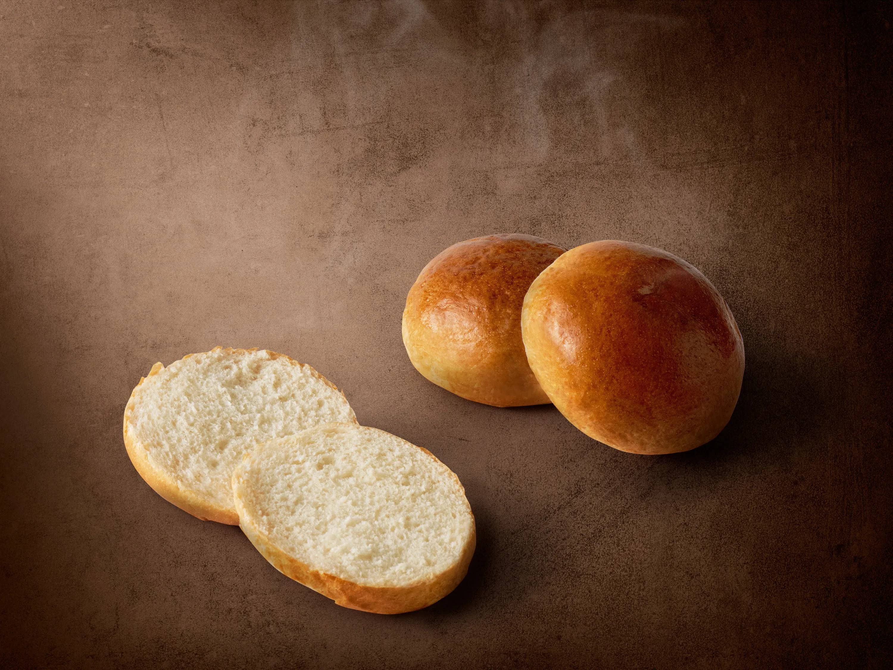 Dwie całe i dwie przekrojone bułki na brązowym tle.